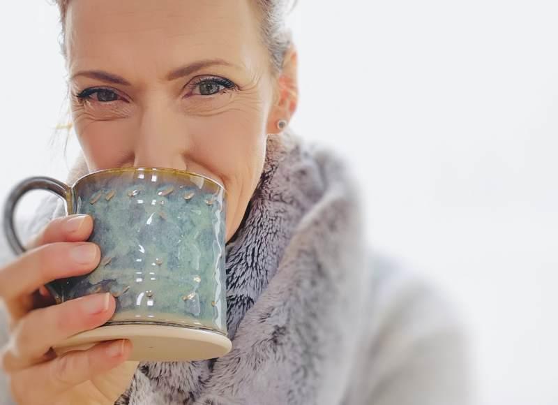 Close-up of a woman enjoying a handcrafted green-blue ceramic mug, showcasing Kilkenny pottery artistry