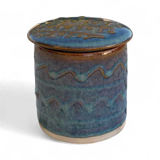 Handcrafted blue and brown ceramic pottery jar with lid, featuring wavy line patterns