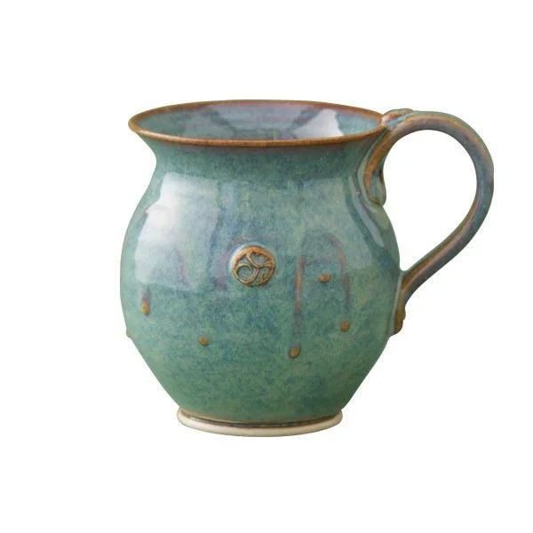 Handcrafted green ceramic mug with round body, decorative emblem, and artisan glazing from Kilkenny pottery