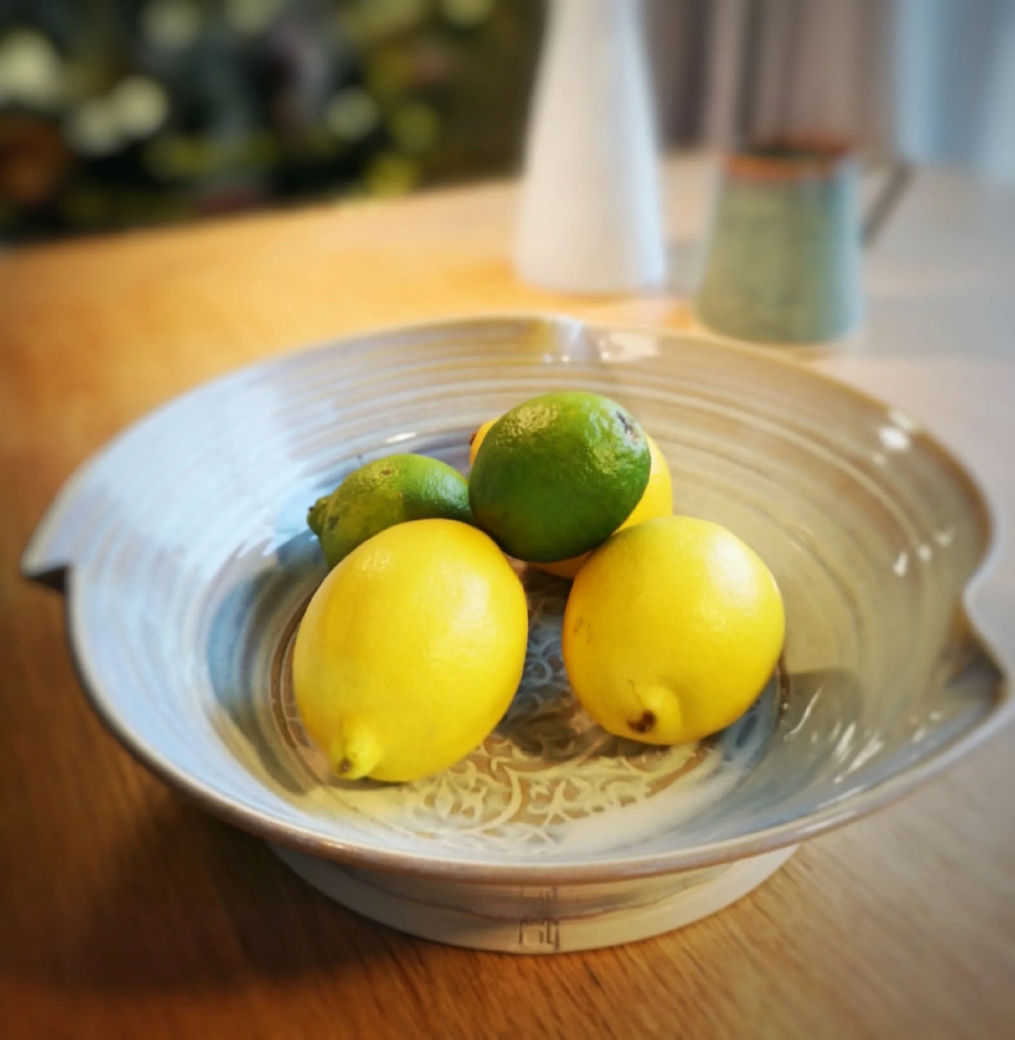 Handcrafted pottery salad bowl with lemons and limes on wooden table, Kilkenny tradition