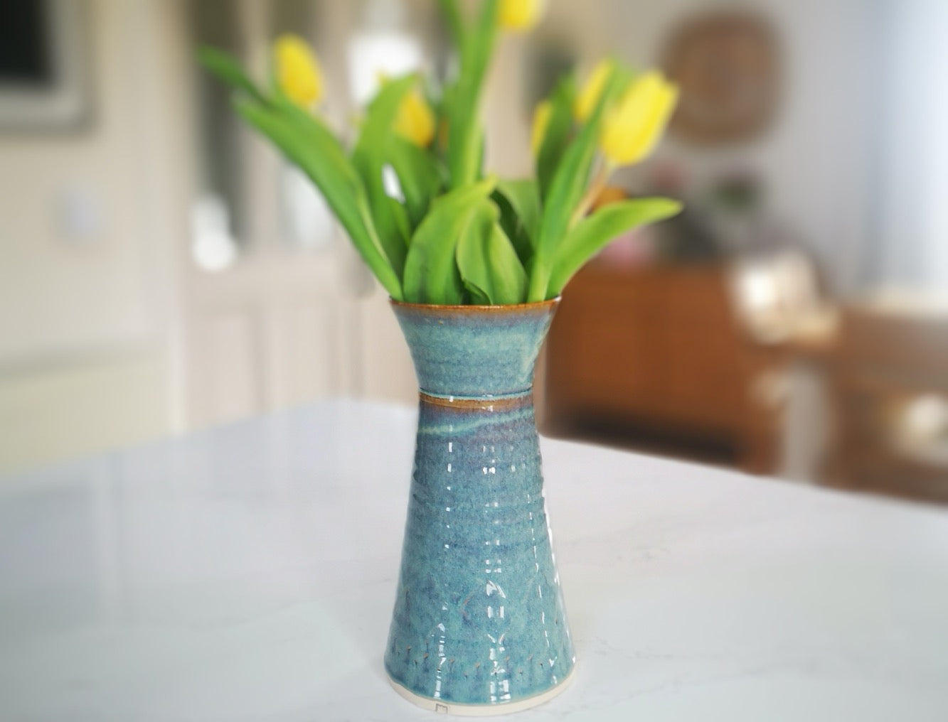 Green Vase with pattern with flowers on a counter top.made by Castle Arch Pottery