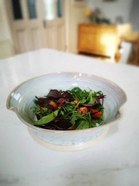 Handmade ceramic salad bowl with fresh mixed greens on kitchen countertop in Kilkenny pottery style